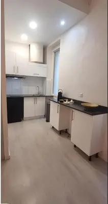 a kitchen with white cabinets and a black counter top at Appartement cosy moderne calme hyper centre gare sncf in Nice