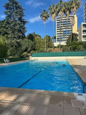 a large blue swimming pool with palm trees and buildings at Terrasses de la Corniche, 2p 65m2 spacieux, terrasses mer & montagne, piscine et parking privé in Nice