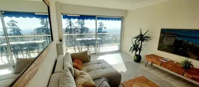 a living room with a couch and a large window at Terrasses de la Corniche, 2p 65m2 spacieux, terrasses mer & montagne, piscine et parking privé in Nice