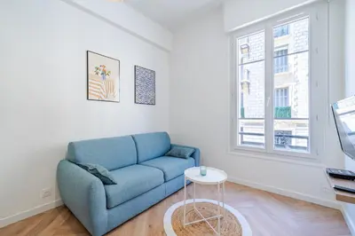 a living room with a blue couch and a table at Studio hypercentre de Nice climatisé in Nice