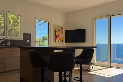 a kitchen with a table with chairs and a television at De la mer aux citronniers in Èze