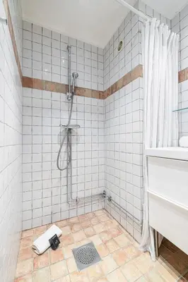 a white tiled bathroom with a shower and a sink at 2 Bdr with Independent Studio - Old Town in Nice