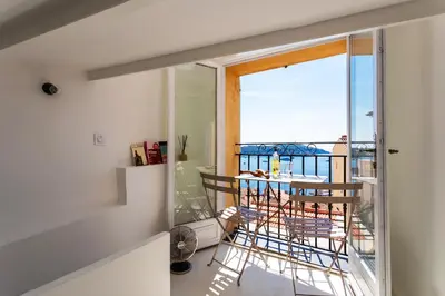 a room with a balcony with a table and chairs at LA CASETTA DI AZZURRA AP4427 By Riviera Holiday Homes in Villefranche-sur-Mer