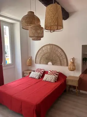 a bedroom with a large red bed with two pillows at Studio climatisé Bohème Chic in Villefranche-sur-Mer