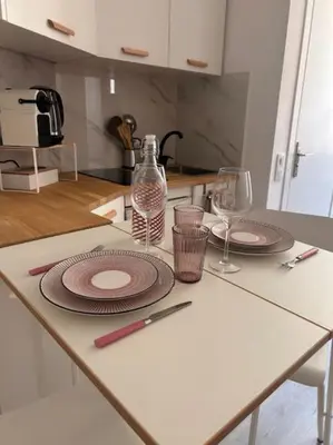a table with plates and wine glasses on it at Studio climatisé Bohème Chic in Villefranche-sur-Mer
