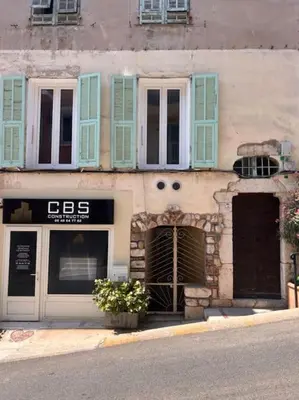 a building with blue shuttered windows and a store at Studio climatisé Bohème Chic in Villefranche-sur-Mer