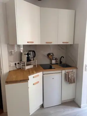 a kitchen with white cabinets and a wooden counter top at Studio climatisé Bohème Chic in Villefranche-sur-Mer