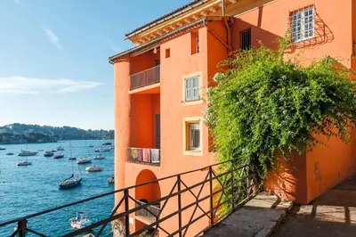a building next to a body of water with boats at Résidence Partenaire Le Palais de la Marine in Villefranche-sur-Mer