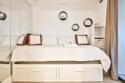 a bedroom with a large white bed with mirrors on the wall at Studio avec grande terrasse YourHostHelper in Villefranche-sur-Mer