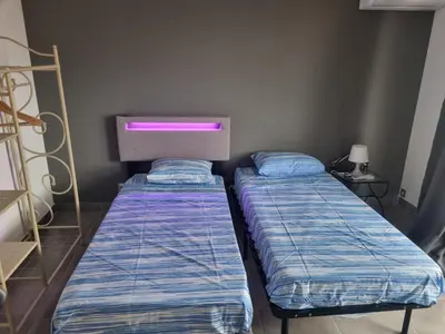 two beds in a small room with a pink light at F2 ou F3 ,appartement climatisé neuf, magnifique vue sur mer et aéroport, proche tram et gare sncf 1 min,aéroport 3 minutes, 3 rooms, new AC apartment, magnificent sea and airport views, close to tram and SNCF train station 1 min, airport 3 min in Nice
