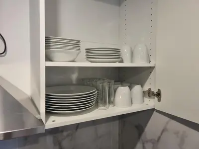 a cupboard with plates and dishes in it at F2 ou F3 ,appartement climatisé neuf, magnifique vue sur mer et aéroport, proche tram et gare sncf 1 min,aéroport 3 minutes, 3 rooms, new AC apartment, magnificent sea and airport views, close to tram and SNCF train station 1 min, airport 3 min in Nice