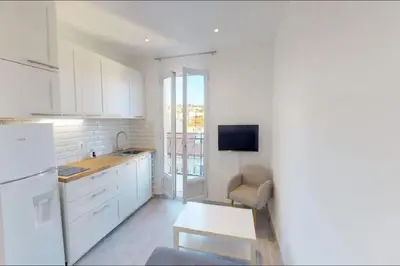 a kitchen with white cabinets and a table and a tv at Appt 2 pièces 43 Avenue Jean Médecin in Nice