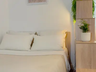 a white bed with white pillows and a potted plant at Central Studio - Bright & Modern - Private Terrace - AirCon - Near Train & Beach in Nice