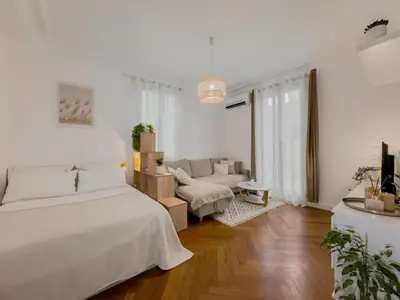 a white bedroom with a bed and a couch at Central Studio - Bright & Modern - Private Terrace - AirCon - Near Train & Beach in Nice