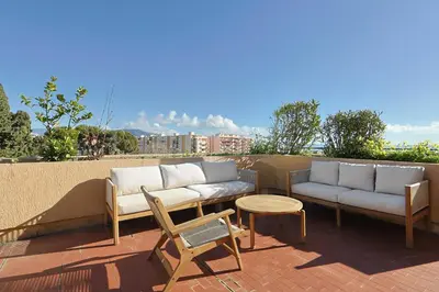 a patio with two couches and a table and chairs at Vue mer sublime, terrasse ensoleillée et parking in Nice