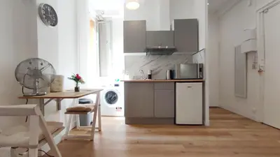 a white kitchen with a table and a refrigerator at Appartement port et vieux Nice Direct from Airport by tramway in Nice
