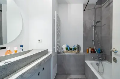 a bathroom with a sink and a tub and a mirror at Superbe 2 pièces Clim et Parking in Nice