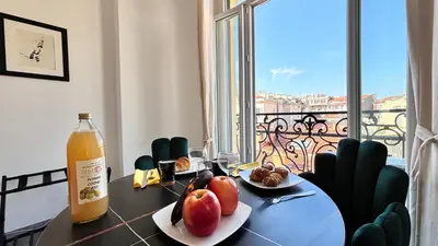 a dining room table with a bottle of orange juice and fruit at Ze Perfect Place - Studio centre-ville - Masséna in Nice