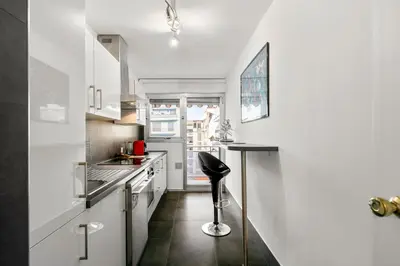 a small kitchen with white cabinets and a black stool at Suite Prestige FSHH in Nice