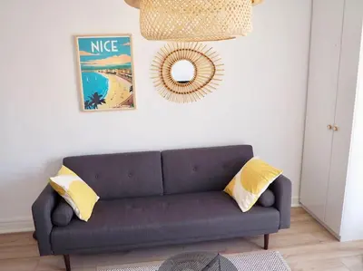 a living room with a blue couch and a mirror at Appartement proche de Libération avec balcon ensoleillé in Nice