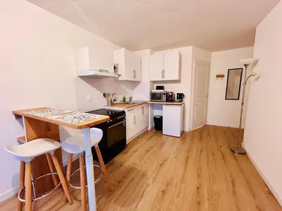 a small kitchen with white cabinets and a wooden floor at City & Serenity - Studio Proche Gare in Nice
