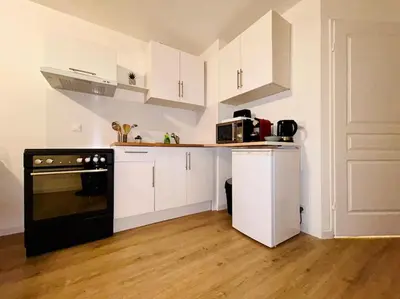 a kitchen with white cabinets and a black oven at City & Serenity - Studio Proche Gare in Nice