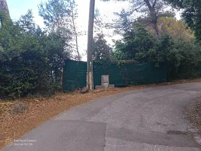 an empty road with a green fence and trees at Studio dans Villa Don Quijote Nice in Nice