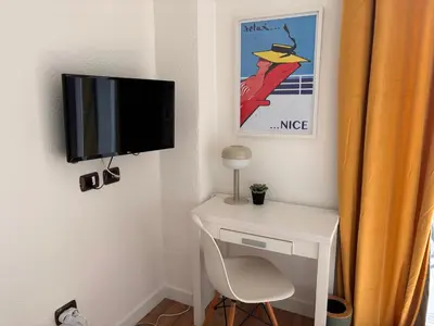 a tv on a wall next to a desk with a chair at Studio gare Nice Clim in Nice