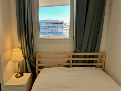 a small bedroom with a bed and a window at Side Ocean View Studio, 24H Check-In and Out, Air Conditioner, Close to Airport in Cagnes-sur-Mer