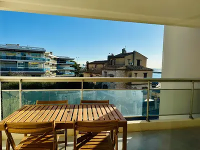 a wooden table and chairs on a balcony with a view at Side Ocean View Studio, 24H Check-In and Out, Air Conditioner, Close to Airport in Cagnes-sur-Mer