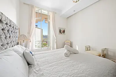 a bedroom with a white bed with a teddy bear on it at 4 pièces vue mer, 6 pers, balcon, WiFi, garage in Villefranche-sur-Mer