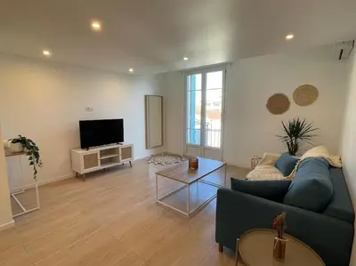 a living room with a blue couch and a tv at Appartement à 2 pas de la mer et Parking privé in Nice