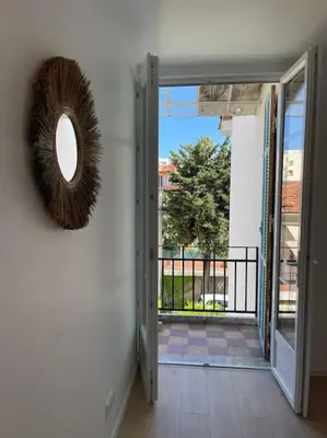 an open door to a balcony with a mirror on the wall at Appartement à 2 pas de la mer et Parking privé in Nice