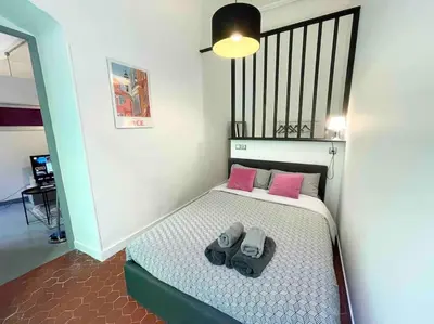 a small bedroom with a bed with pink pillows at Cosy appartement, moderne, fuchsia, industriel in Nice