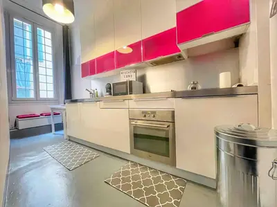 a kitchen with red cabinets and an oven at Cosy appartement, moderne, fuchsia, industriel in Nice