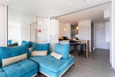 a living room with a blue couch and a kitchen at Esterel AP4431 By Riviera Holiday Homes in Villefranche-sur-Mer