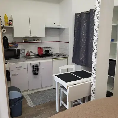 a small kitchen with white cabinets and a table at Studio centre ville in Nice