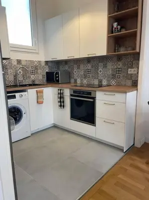 a kitchen with white cabinets and a washer and dryer at Appartement Niçois in Nice
