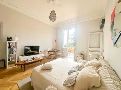 a white bedroom with a large bed and a living room at Appartement exceptionnel belle époque avec grande terrasse plein sud in Nice