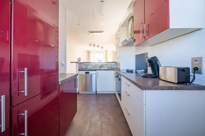 a kitchen with red cabinets and white counters at Superbe 3p vue mer avec parking in Nice