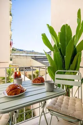 a table with food on a balcony with a plant at Charming Apt Nice Port Place du Pin with Balcony in Nice