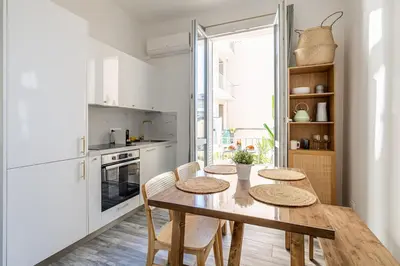 a kitchen with a wooden table and chairs and a kitchen with white appliances at Charming Apt Nice Port Place du Pin with Balcony in Nice