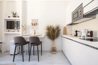 a white kitchen with a table and chairs at 1 GAUTIER 501 - Studio boheme - Quartier du port in Nice