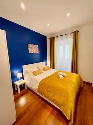 a bedroom with a large bed with a blue wall at Le Village - cosy flat 5 min walk away from sea in Nice