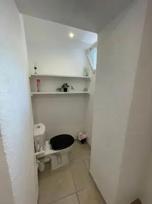 a white bathroom with a toilet with a black seat at Le Village - cosy flat 5 min walk away from sea in Nice