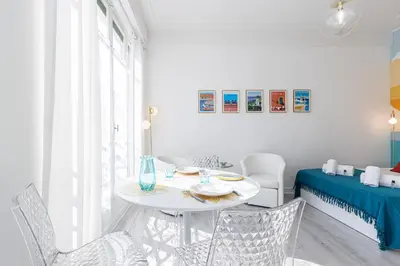a white dining room with a white table and chairs at 37 LAMARTINE - Magnifique Studio Art Deco - Centre-ville in Nice