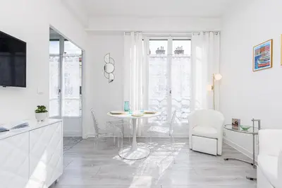 a white living room with a table and chairs at 37 LAMARTINE - Magnifique Studio Art Deco - Centre-ville in Nice