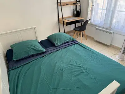 a bed with a green comforter in a bedroom at Studio lumineux in Nice