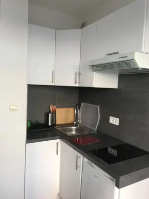 a kitchen with white cabinets and a sink and a stove at Studio lumineux in Nice