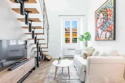 a living room with a white couch and a spiral staircase at 5 FODERE - Magnifique Duplex - Port de Nice - Dernier etage in Nice